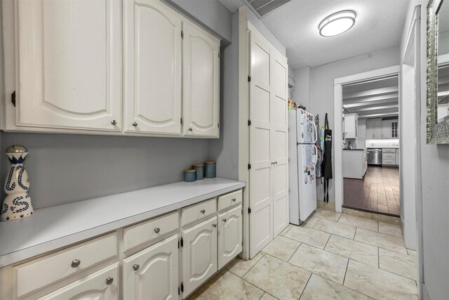 kitchen featuring white cabinets, white refrigerator, stainless steel dishwasher, and light wood-type flooring