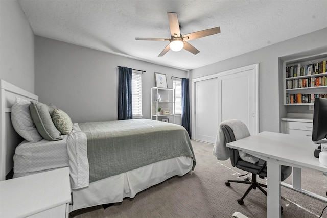 bedroom with a closet, a textured ceiling, light colored carpet, and ceiling fan