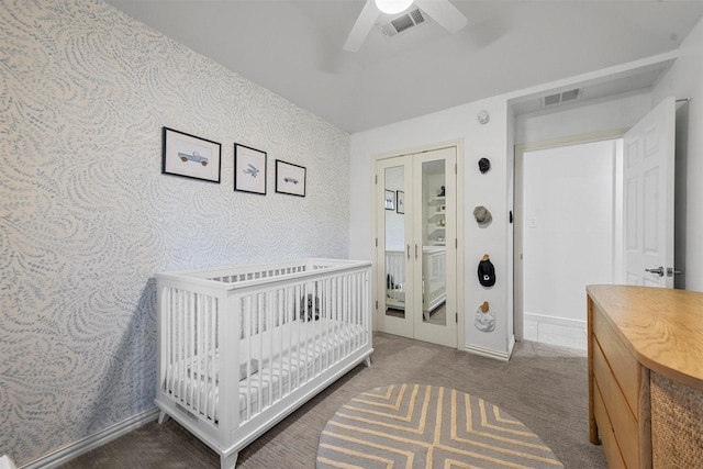 carpeted bedroom featuring ceiling fan and a crib