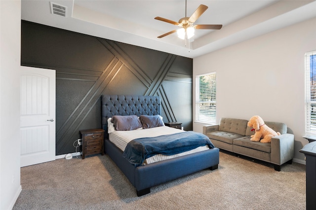 bedroom with a raised ceiling, ceiling fan, and carpet