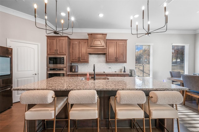 kitchen featuring stainless steel microwave, sink, dark hardwood / wood-style flooring, crown molding, and an island with sink