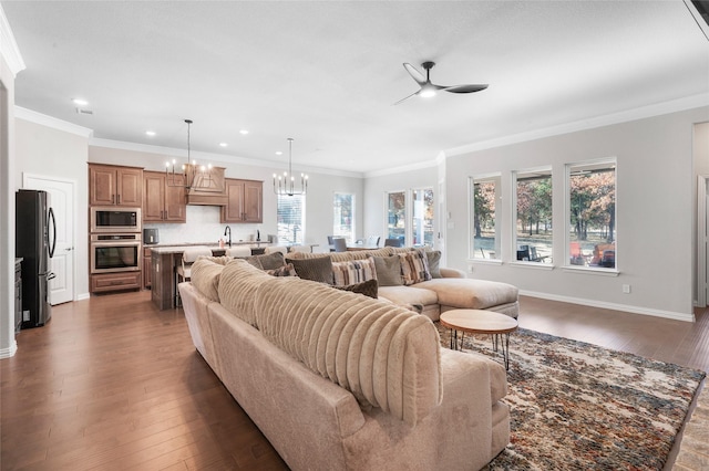 living room featuring ceiling fan with notable chandelier, dark hardwood / wood-style flooring, plenty of natural light, and crown molding