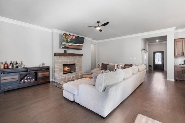 living room featuring dark hardwood / wood-style flooring, a stone fireplace, ceiling fan, and ornamental molding