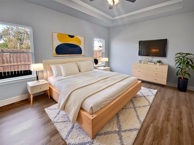 bedroom featuring dark hardwood / wood-style flooring, a tray ceiling, ceiling fan, and ornamental molding