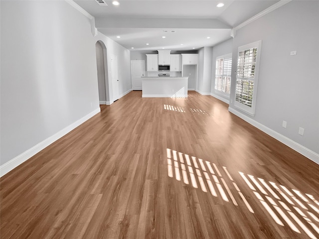 unfurnished living room with light wood-type flooring, ornamental molding, and vaulted ceiling