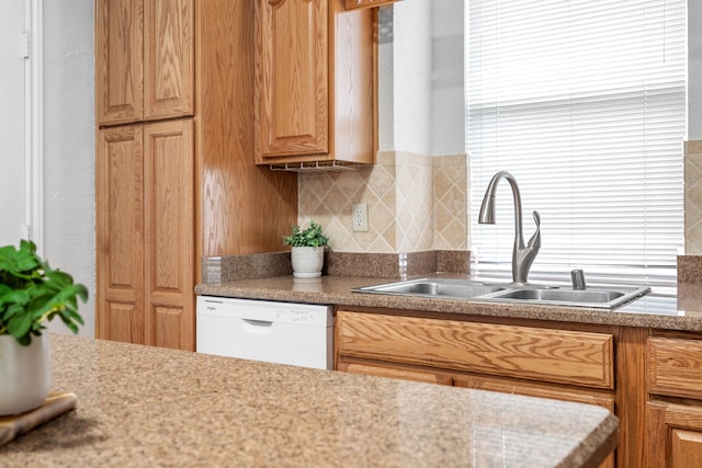 kitchen featuring light countertops, tasteful backsplash, white dishwasher, and a sink