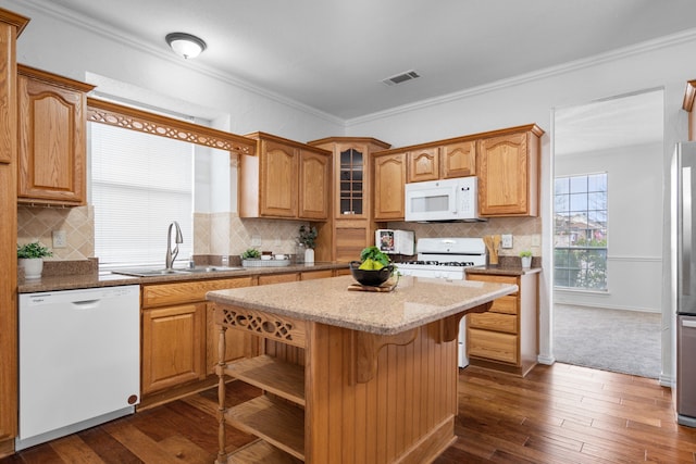 kitchen with white appliances, visible vents, a center island, crown molding, and a sink