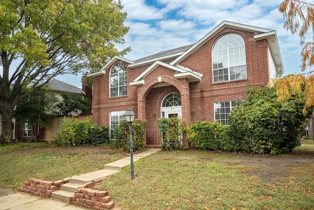 traditional-style house with brick siding, fence, and a front lawn