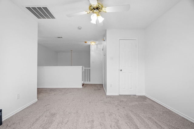 carpeted empty room with baseboards, visible vents, and a ceiling fan