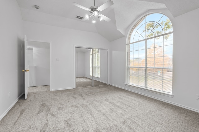 unfurnished bedroom featuring lofted ceiling, a closet, carpet flooring, and multiple windows