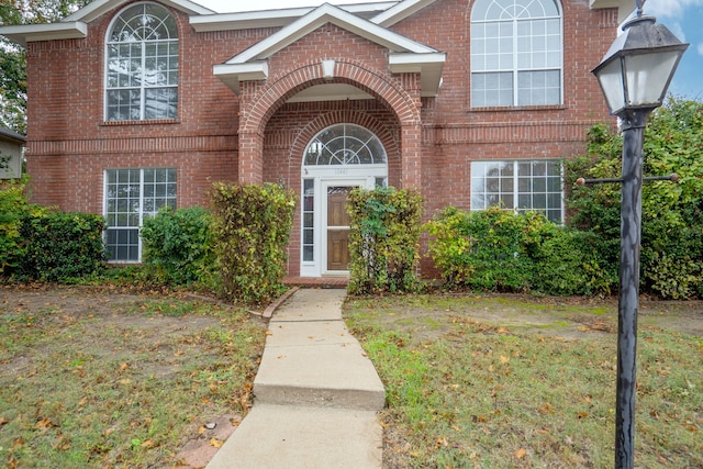 doorway to property with a yard and brick siding