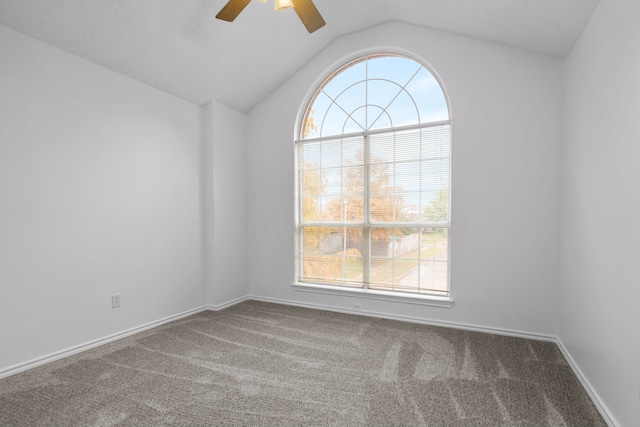 carpeted spare room featuring lofted ceiling, ceiling fan, and baseboards