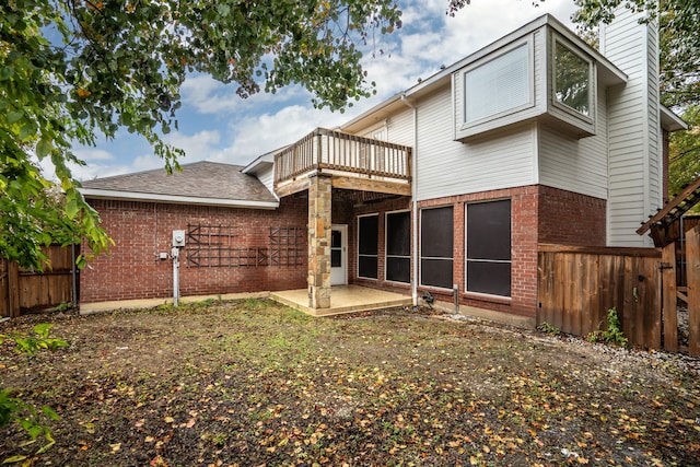 rear view of property with a balcony, brick siding, fence, a chimney, and a patio area