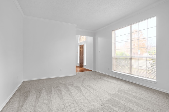 empty room featuring a textured ceiling, ornamental molding, carpet flooring, and baseboards