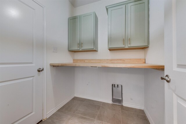 laundry area featuring electric dryer hookup, light tile patterned flooring, and cabinets