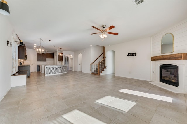 unfurnished living room featuring light tile patterned floors and ceiling fan with notable chandelier