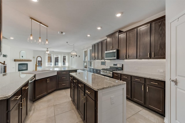 kitchen with sink, a kitchen island, decorative light fixtures, and appliances with stainless steel finishes