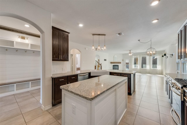 kitchen with ceiling fan, sink, a center island, stainless steel appliances, and light stone counters