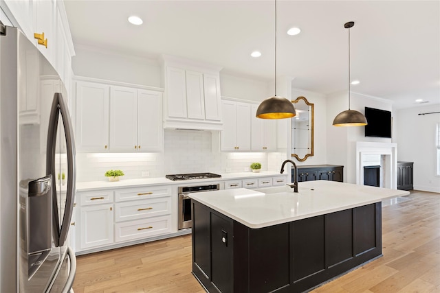 kitchen featuring white cabinetry, light hardwood / wood-style flooring, pendant lighting, a kitchen island with sink, and appliances with stainless steel finishes