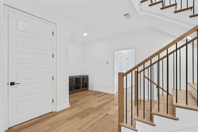 stairway with hardwood / wood-style floors and ornamental molding