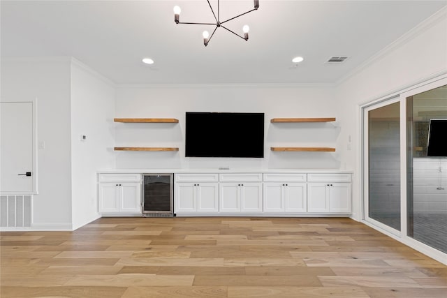 interior space with wine cooler, an inviting chandelier, light wood-type flooring, and ornamental molding