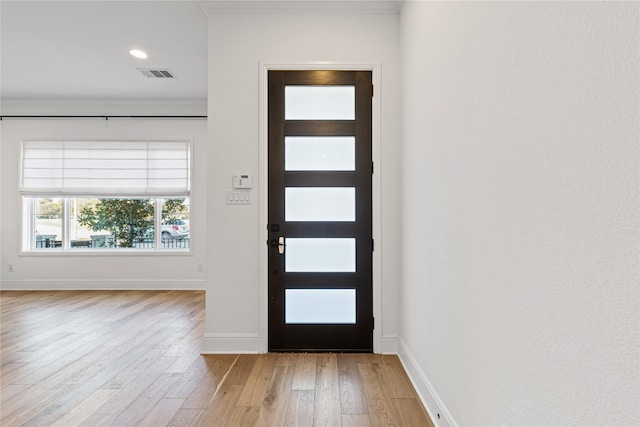 foyer entrance with crown molding and light wood-type flooring