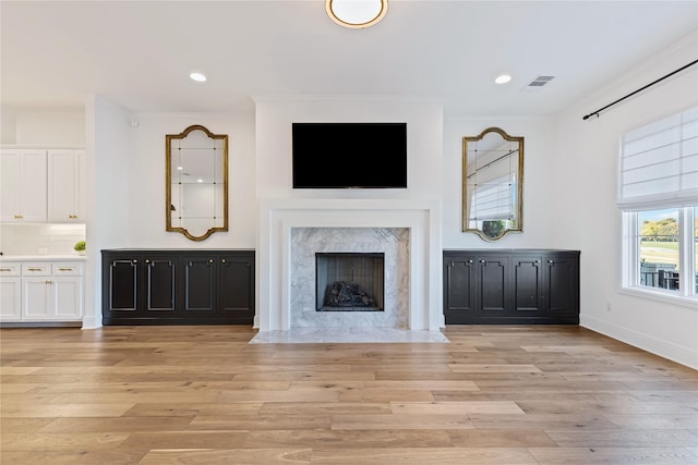 unfurnished living room with a high end fireplace and light hardwood / wood-style floors