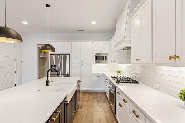 kitchen featuring white cabinets, appliances with stainless steel finishes, light stone counters, and pendant lighting