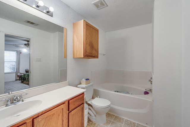 bathroom featuring vanity, ceiling fan, toilet, a textured ceiling, and a tub to relax in