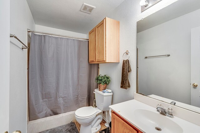 bathroom with a textured ceiling, vanity, toilet, and walk in shower