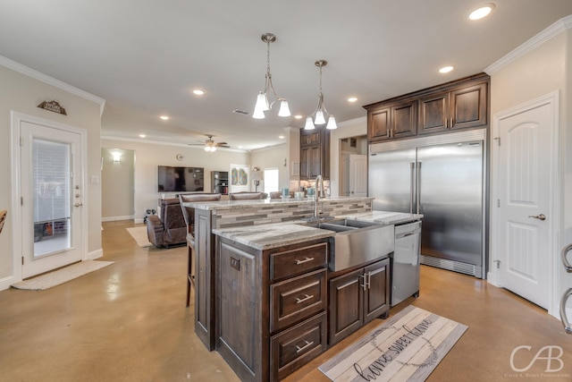 kitchen with tasteful backsplash, decorative light fixtures, stainless steel appliances, and a kitchen island with sink