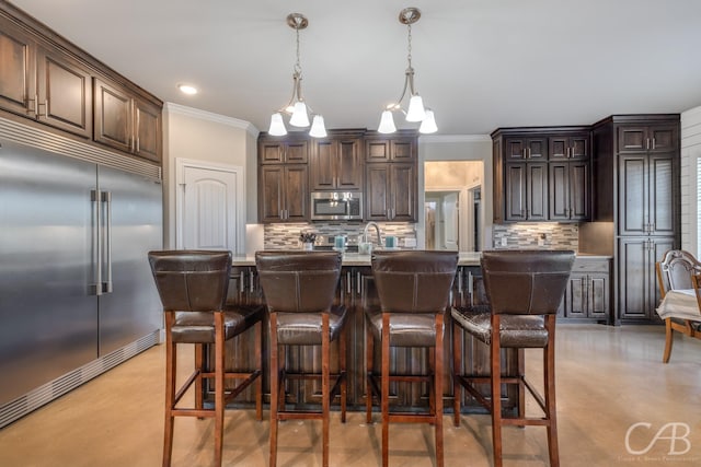 kitchen featuring backsplash, dark brown cabinetry, stainless steel appliances, and a kitchen island with sink