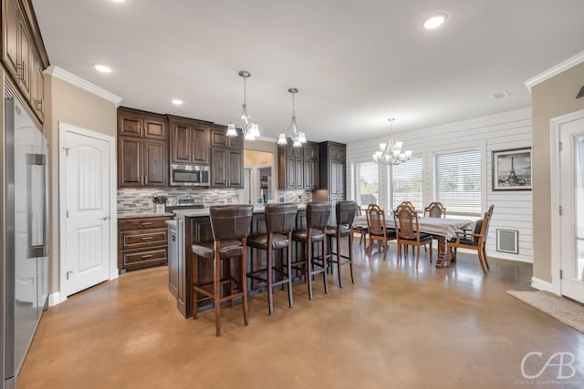 kitchen with hanging light fixtures, tasteful backsplash, concrete flooring, a kitchen island with sink, and appliances with stainless steel finishes