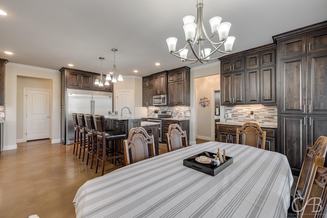 dining area featuring a chandelier, ornamental molding, sink, and concrete floors