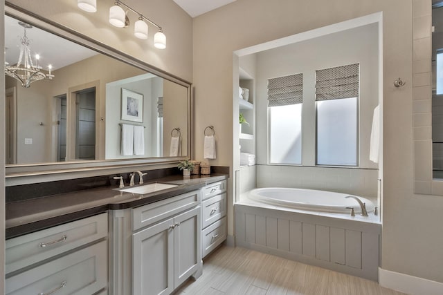 bathroom featuring vanity, a bath, and a chandelier