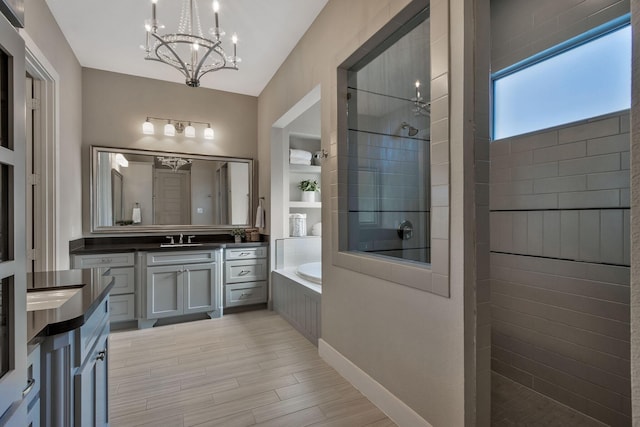 bathroom featuring vanity, plus walk in shower, and an inviting chandelier