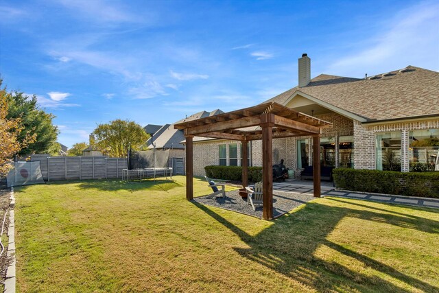 rear view of property featuring a patio, an outdoor fire pit, a trampoline, and a lawn