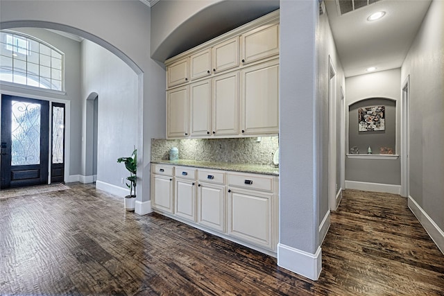 interior space featuring dark hardwood / wood-style floors, light stone counters, and tasteful backsplash