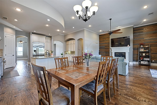 dining area with ceiling fan with notable chandelier, wood walls, and dark wood-type flooring