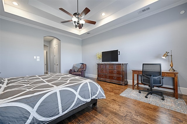 bedroom with ornamental molding, a tray ceiling, ceiling fan, and hardwood / wood-style flooring