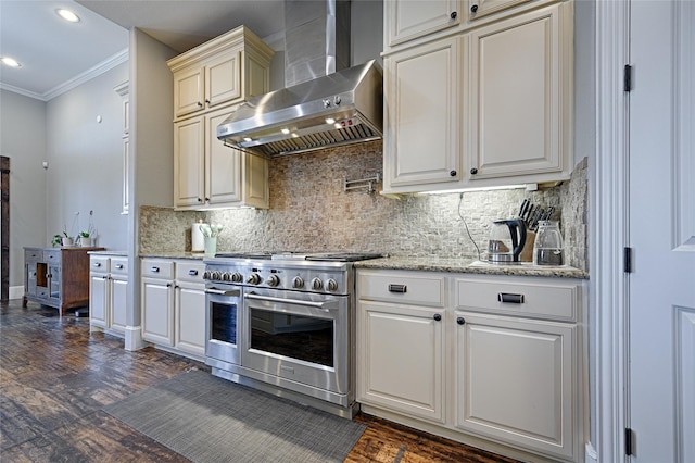 kitchen with tasteful backsplash, ornamental molding, dark wood-type flooring, wall chimney range hood, and double oven range