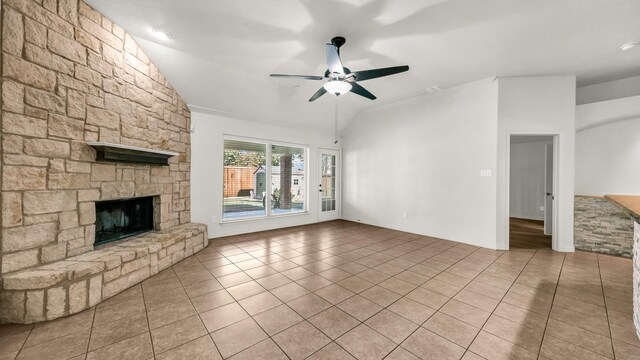 unfurnished living room featuring lofted ceiling, visible vents, a ceiling fan, a stone fireplace, and tile patterned flooring