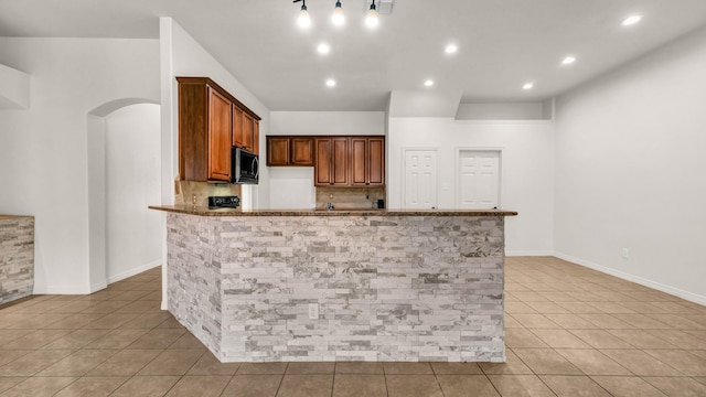 kitchen with decorative backsplash, dark stone countertops, and light tile patterned floors