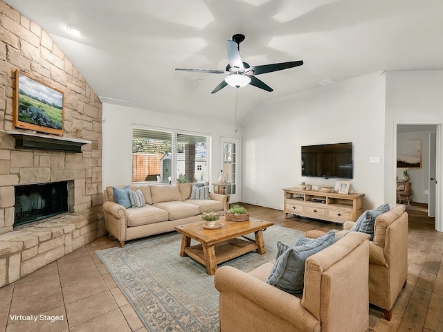 living area with ceiling fan, a fireplace, vaulted ceiling, and tile patterned floors