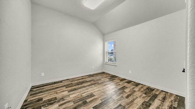 empty room featuring vaulted ceiling and hardwood / wood-style flooring