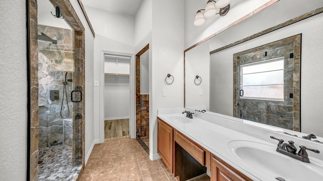 full bathroom with tile patterned floors, a sink, a shower stall, and a spacious closet