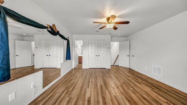 unfurnished bedroom with light wood finished floors, baseboards, visible vents, and multiple closets