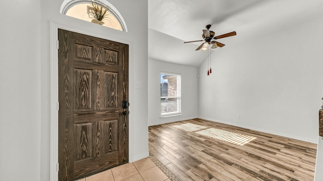 entrance foyer with light wood finished floors, baseboards, vaulted ceiling, and a ceiling fan