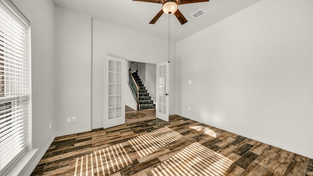 empty room with dark hardwood / wood-style floors, ceiling fan, and french doors