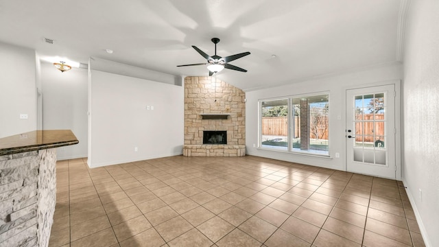 unfurnished living room featuring a stone fireplace, vaulted ceiling, ceiling fan, light tile patterned floors, and ornamental molding